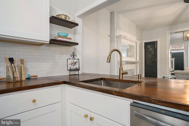 kitchen featuring white cabinetry, butcher block countertops, sink, and dishwasher