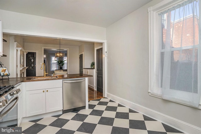 kitchen with butcher block counters, sink, decorative light fixtures, stainless steel appliances, and white cabinets