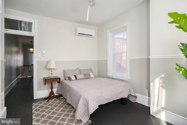 bedroom with an AC wall unit and hardwood / wood-style floors