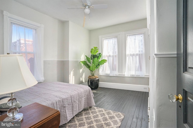 bedroom with multiple windows, wood-type flooring, and ceiling fan