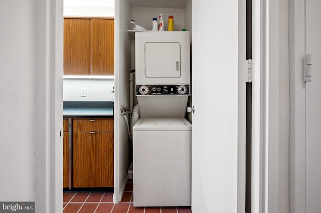 laundry area with stacked washer and dryer and dark tile patterned floors