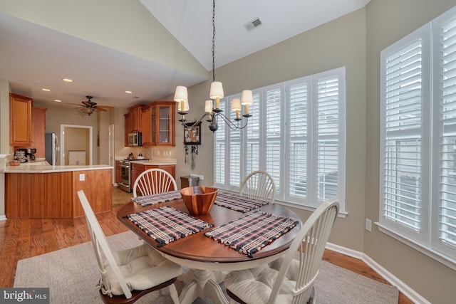 dining space featuring lofted ceiling, ceiling fan with notable chandelier, and light hardwood / wood-style flooring