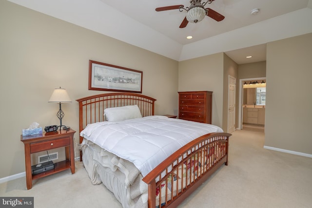 bedroom with vaulted ceiling, connected bathroom, light carpet, and ceiling fan