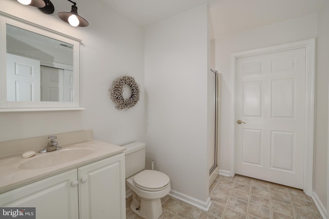 bathroom with vanity, a shower with door, and toilet