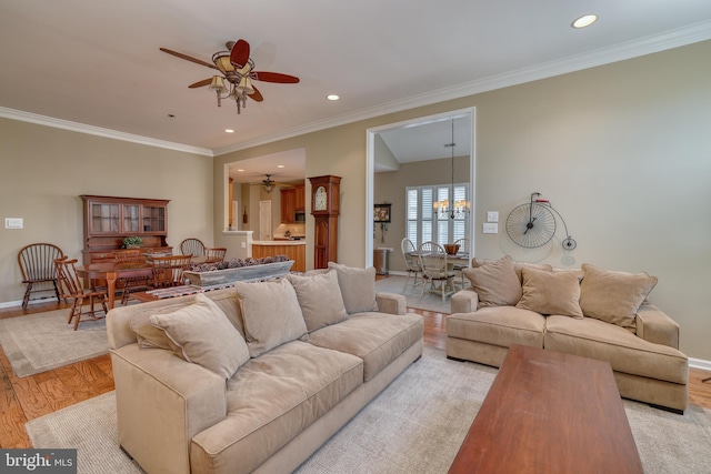 living room featuring crown molding, ceiling fan with notable chandelier, and light wood-type flooring