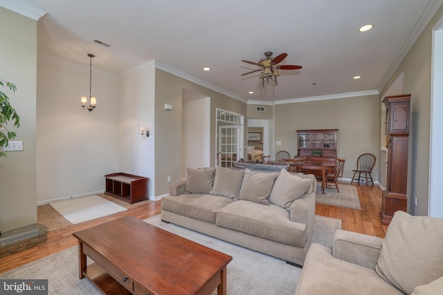 living room with crown molding, ceiling fan with notable chandelier, and light hardwood / wood-style flooring