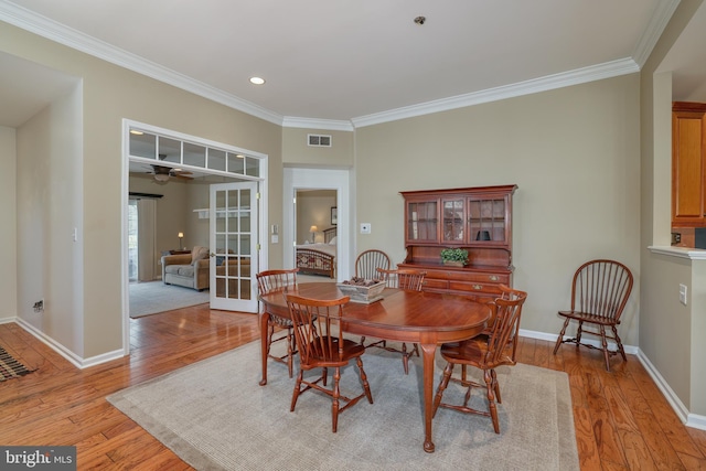 dining room with ornamental molding and light hardwood / wood-style flooring