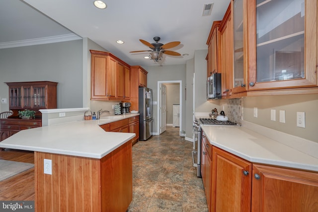 kitchen featuring appliances with stainless steel finishes, a breakfast bar, sink, ceiling fan, and kitchen peninsula