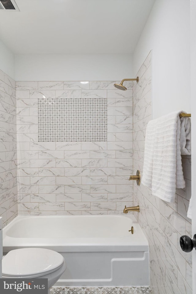 bathroom featuring tiled shower / bath combo and toilet