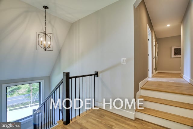 stairs with hardwood / wood-style flooring, an inviting chandelier, and vaulted ceiling