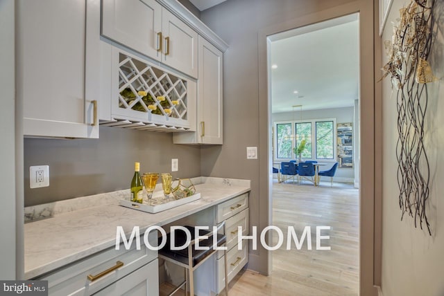 bar with white cabinets and light stone counters