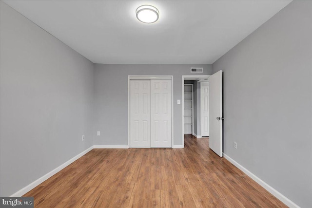 unfurnished bedroom featuring wood-type flooring and a closet