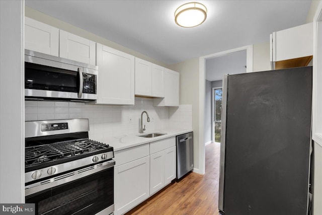 kitchen with appliances with stainless steel finishes, sink, white cabinets, and backsplash