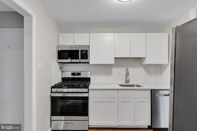 kitchen with sink, white cabinetry, stainless steel appliances, light stone counters, and tasteful backsplash