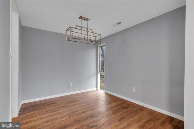 unfurnished room with hardwood / wood-style floors and an inviting chandelier