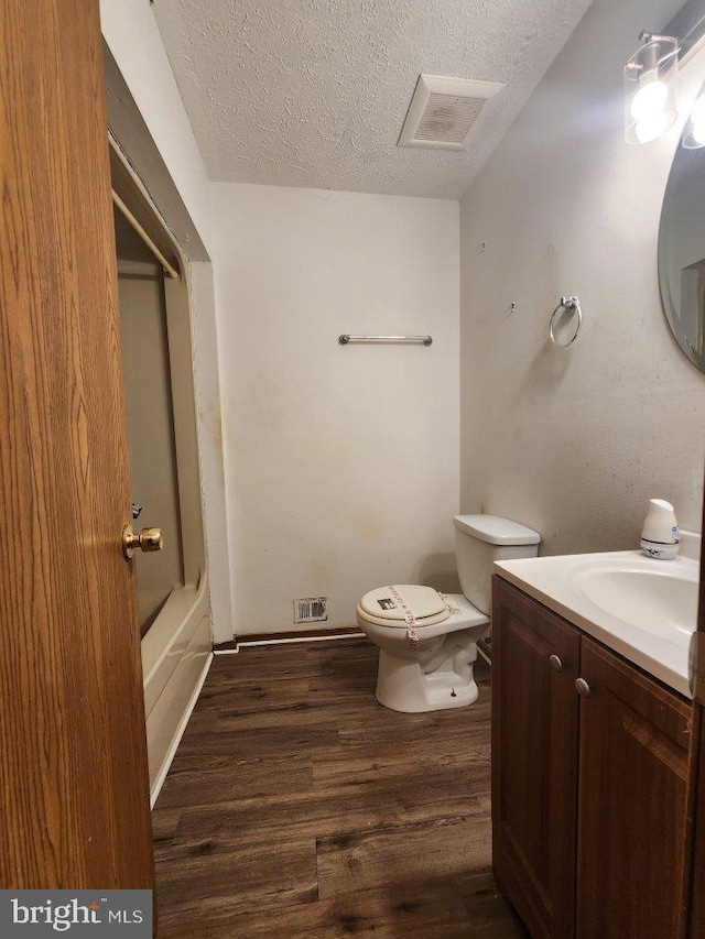 6212 8th St, Chesapeake Beach, MD 20732 - full bath featuring a textured ceiling, vanity, toilet, wood finished floors, and shower / washtub combination
