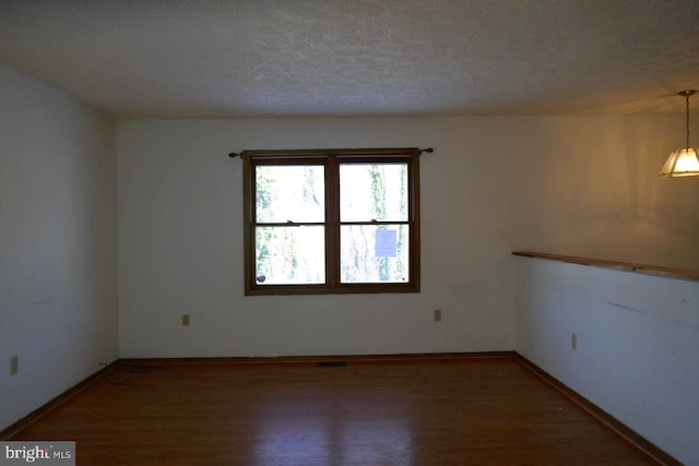 empty room featuring hardwood / wood-style flooring and a textured ceiling