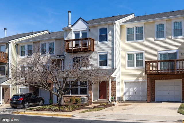 townhome / multi-family property with a garage, brick siding, central AC unit, and driveway