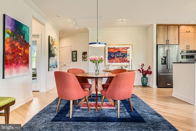 dining room with rail lighting, ornamental molding, light wood finished floors, and baseboards