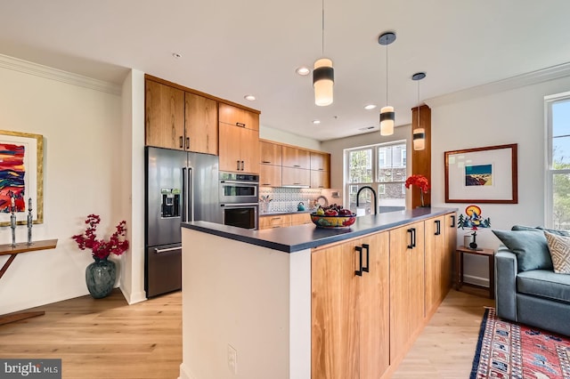 kitchen featuring stainless steel appliances, dark countertops, a peninsula, and light wood-style flooring