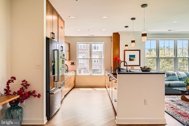 kitchen with a sink, dark countertops, baseboards, recessed lighting, and stainless steel fridge