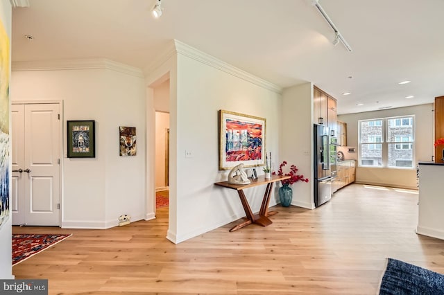 hallway with rail lighting, light wood-type flooring, and baseboards