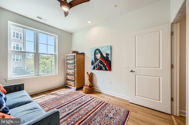 sitting room with baseboards, visible vents, ceiling fan, and light wood finished floors