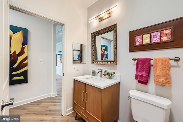 bathroom featuring toilet, wood finished floors, vanity, and baseboards