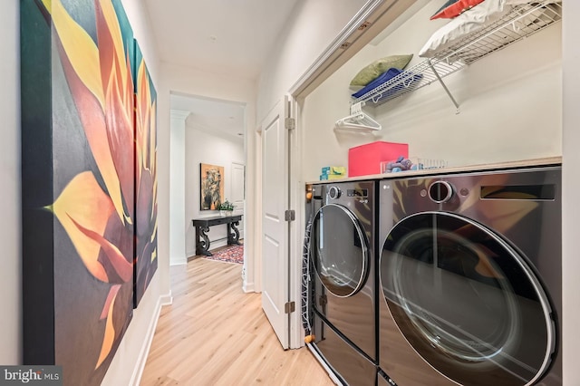 laundry room with wood finished floors, baseboards, laundry area, and washing machine and dryer