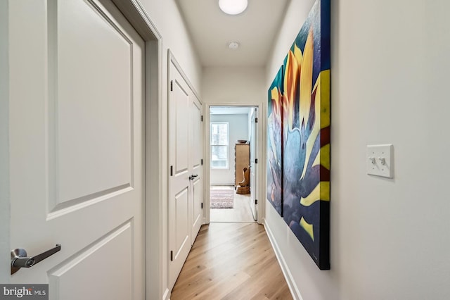hallway featuring light wood-type flooring and baseboards