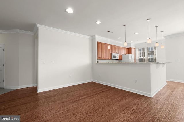 kitchen with brown cabinets, white appliances, pendant lighting, ornamental molding, and wood finished floors