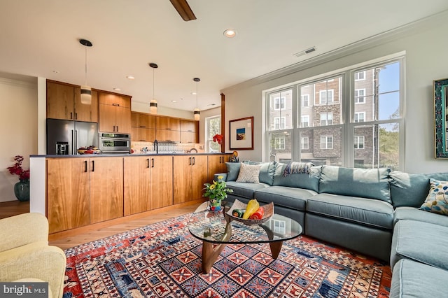 living area with wood finished floors, visible vents, crown molding, and recessed lighting