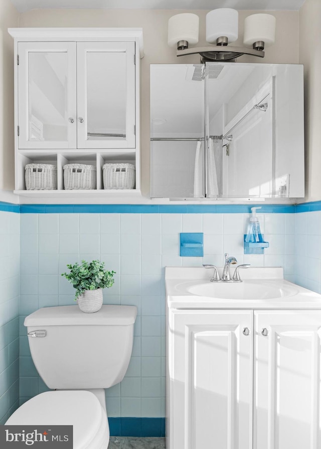 full bath featuring toilet, vanity, and tile walls