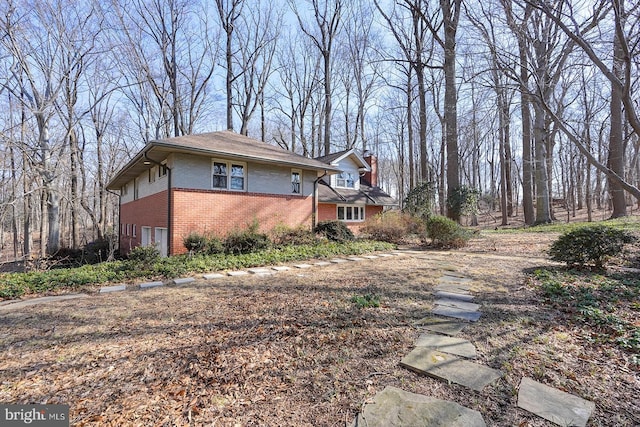 view of home's exterior featuring brick siding and a chimney