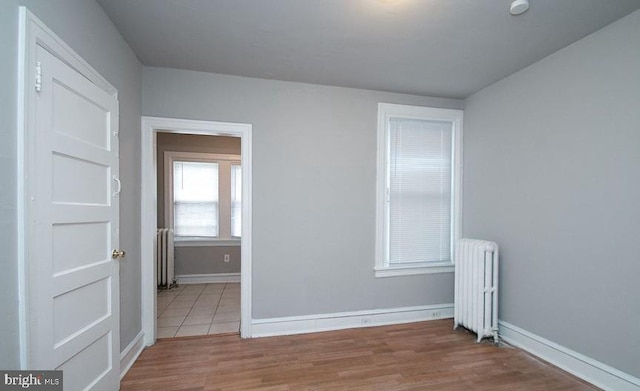 spare room featuring radiator heating unit and light hardwood / wood-style flooring