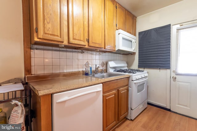 kitchen featuring sink, backsplash, white appliances, and light hardwood / wood-style flooring