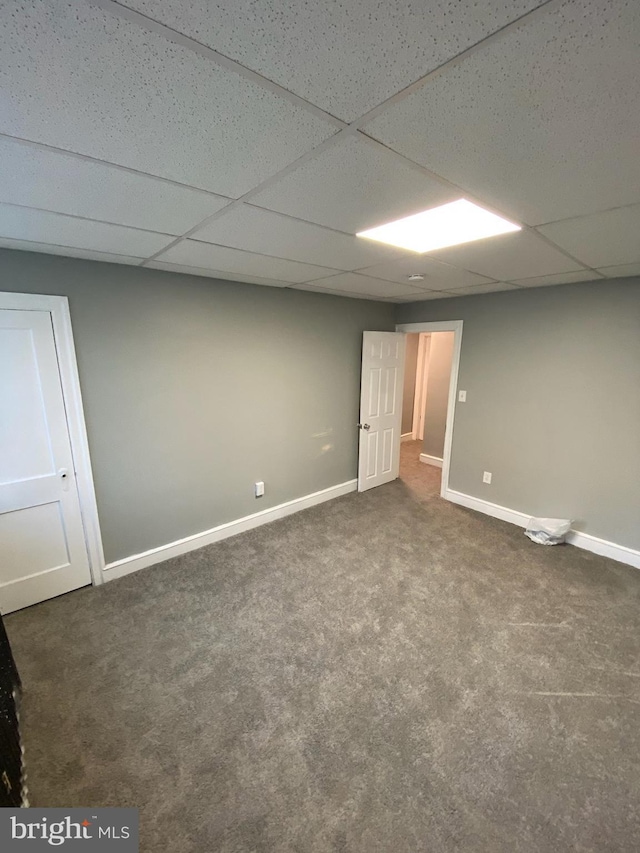 basement with a drop ceiling and dark colored carpet