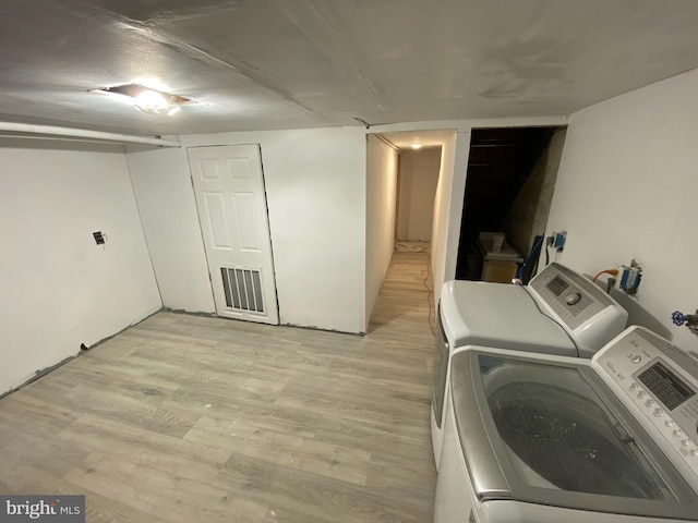 laundry room with washing machine and clothes dryer and light hardwood / wood-style floors