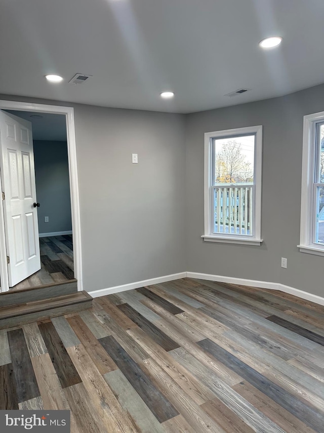 spare room with visible vents, baseboards, and wood finished floors