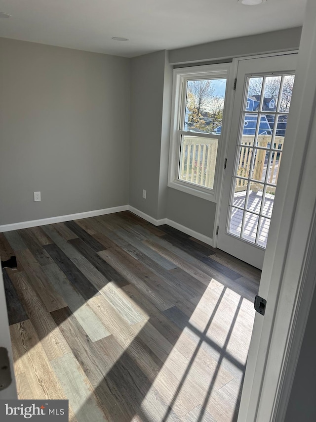 unfurnished room with dark wood finished floors and baseboards