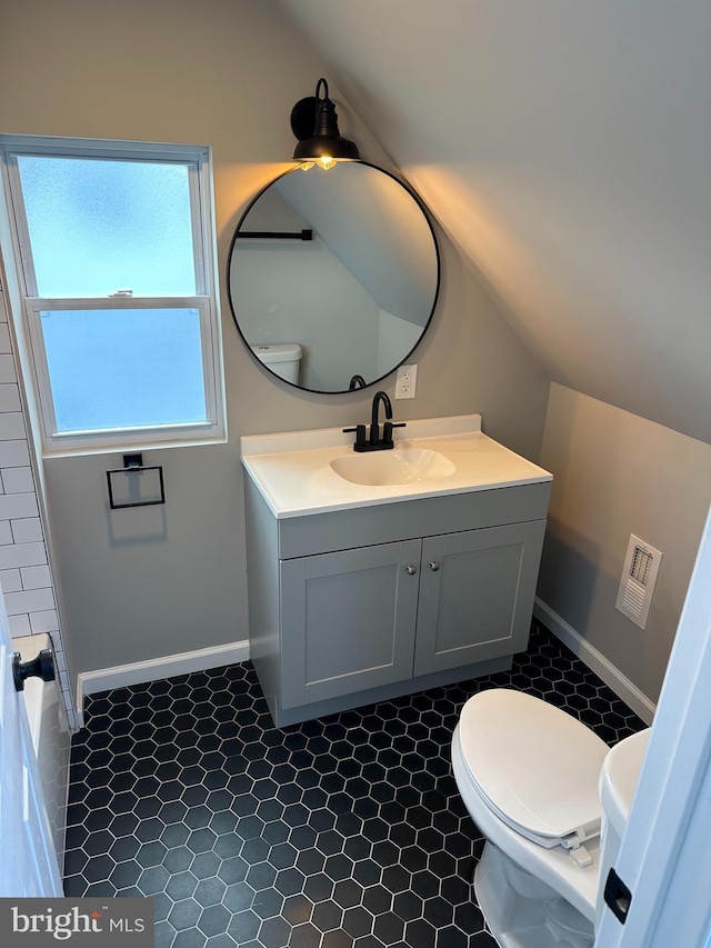 bathroom featuring lofted ceiling, visible vents, toilet, vanity, and baseboards