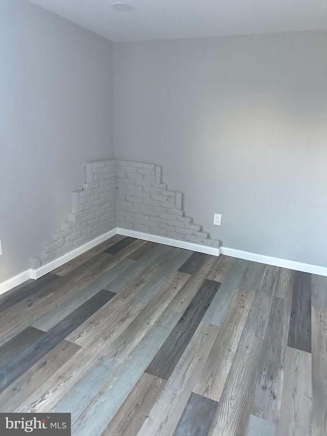 empty room featuring wood finished floors and baseboards