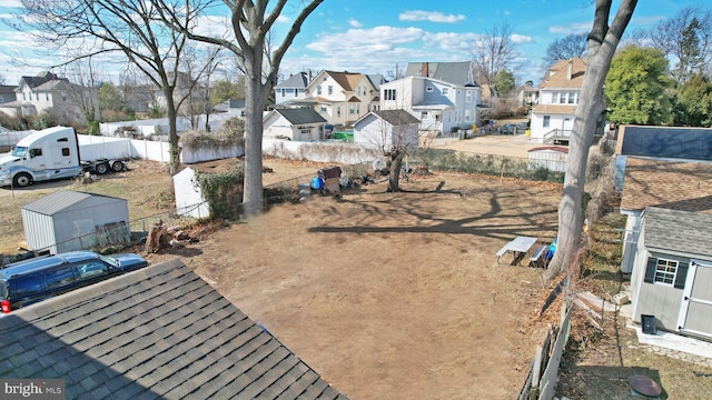 view of yard featuring a residential view, fence, an outbuilding, and a storage unit