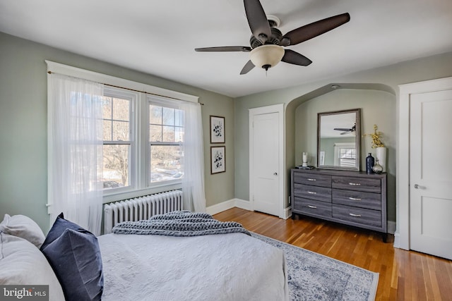 bedroom featuring hardwood / wood-style flooring, ceiling fan, and radiator