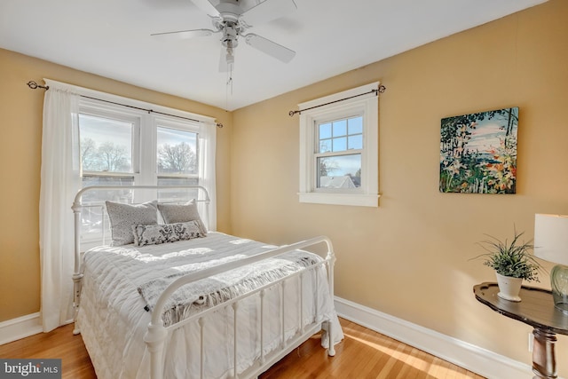 bedroom featuring multiple windows, hardwood / wood-style flooring, and ceiling fan