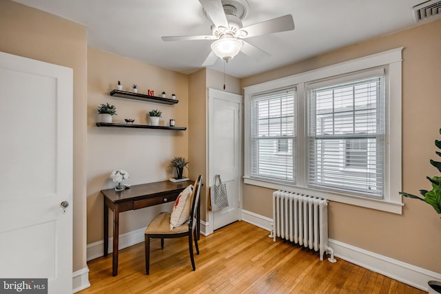 office featuring radiator heating unit, ceiling fan, and light wood-type flooring