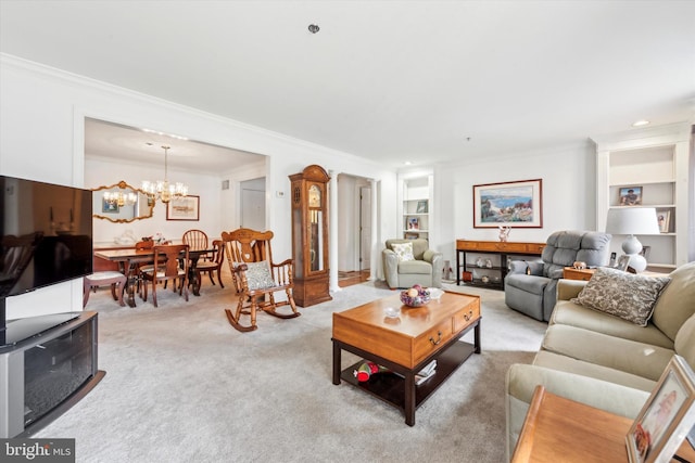 carpeted living room featuring ornamental molding, an inviting chandelier, and built in shelves