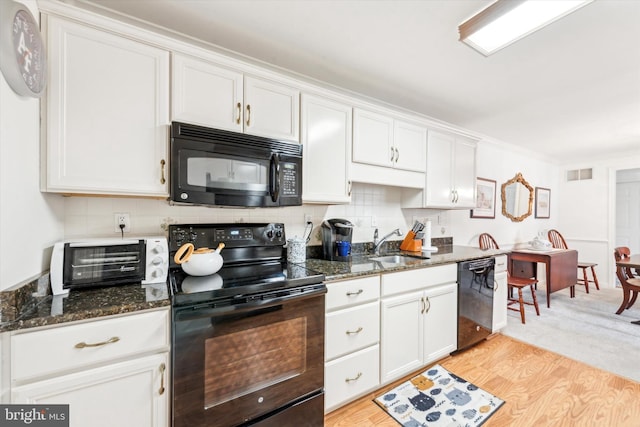 kitchen with sink, white cabinets, backsplash, dark stone counters, and black appliances