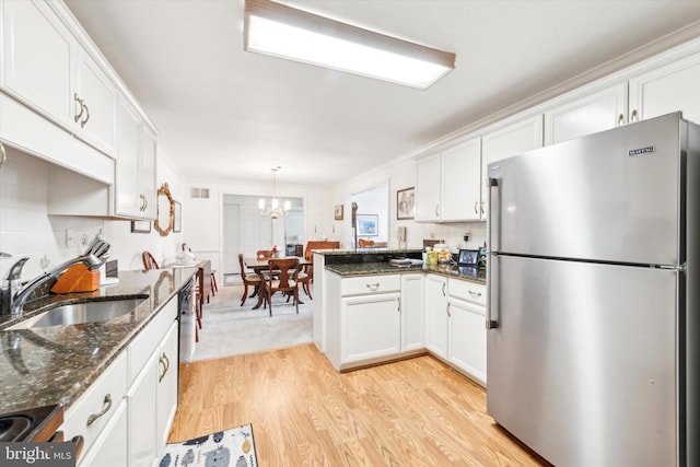 kitchen featuring stainless steel refrigerator, decorative light fixtures, sink, white cabinets, and light hardwood / wood-style floors