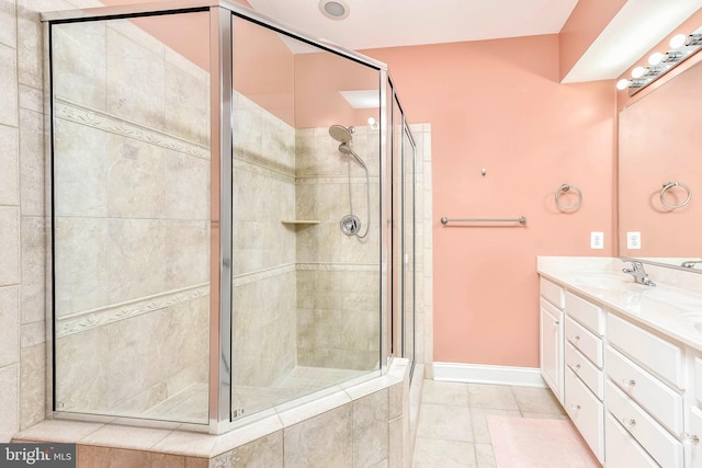 bathroom with a shower with door, vanity, and tile patterned floors